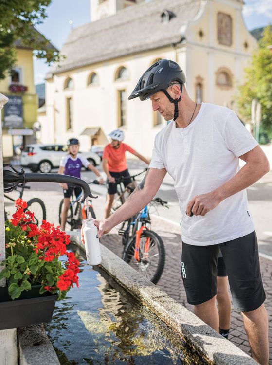 Un ciclista si riempie la boraccia presso una fontana