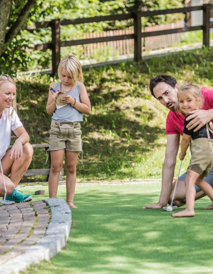 A family is playing minigolf